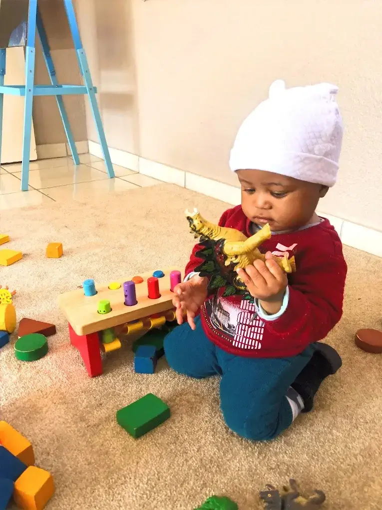 A baby playing with soft toys in the baby room